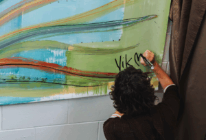 an image of the artist signing the artwork titled He Ara Tatai (loosely translated as “Destined Path”)