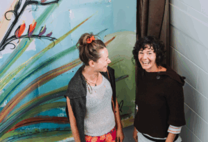 an image of the artist and one other woman standing in front of the artwork titled He Ara Tatai (loosely translated as “Destined Path”)